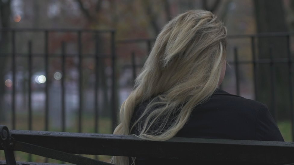 'Alice' sentada de espalda en una banca