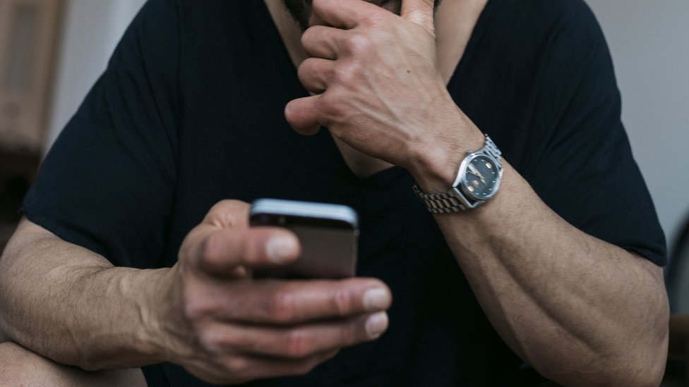 Un hombre en mirando su celular.