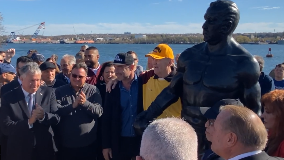 Chuck Wepner, con el gorro amarillo, posa junto a la estatua en su honor en Nueva Jersey.