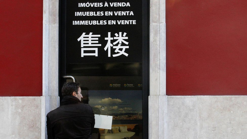 Un hombre frente a una agencia inmobiliaria en Portugal.