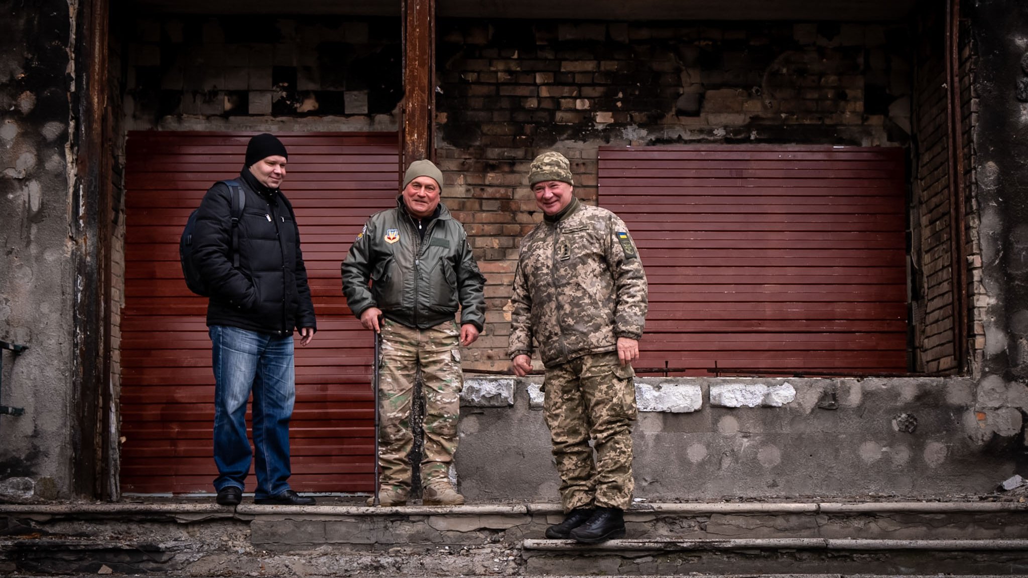 Maksym (izq.) Volodymyr (centro) y "el coronel" (der.) frente a las ruinas bombardeadas de su oficina para voluntarios