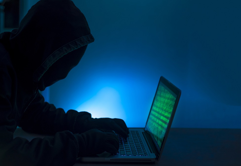 Foto genérica de una hombre a oscuras con una computadora