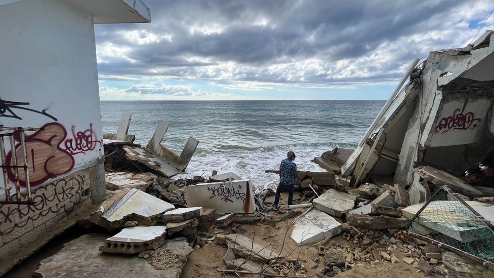 El profesor Ruperto Chaparro camina entre unas ruinas frente a la costa de Rincón, Puerto Rico.