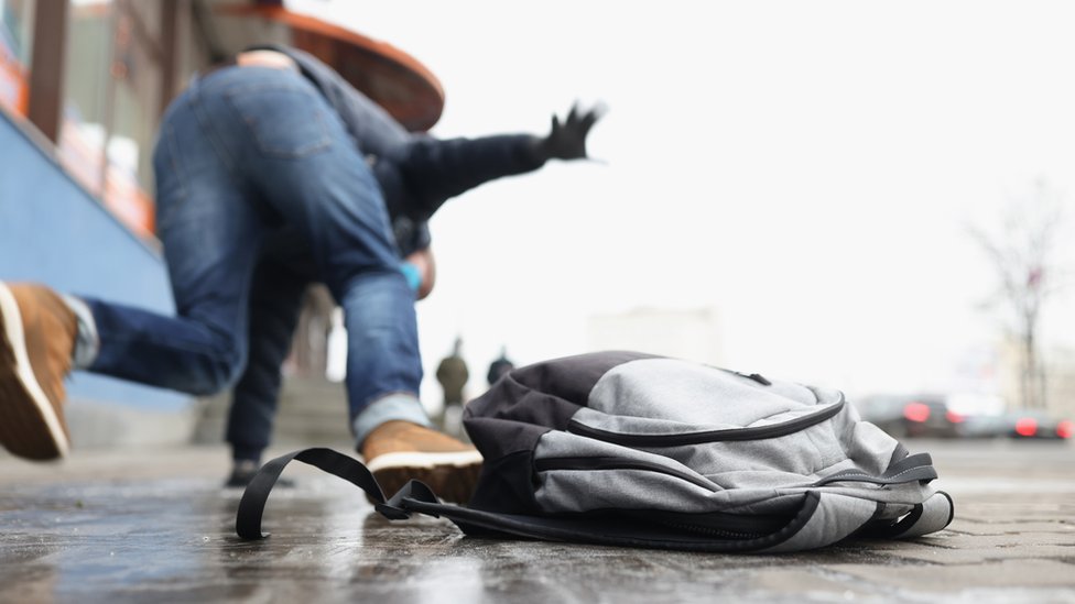 Un hombre se cae en una acera.