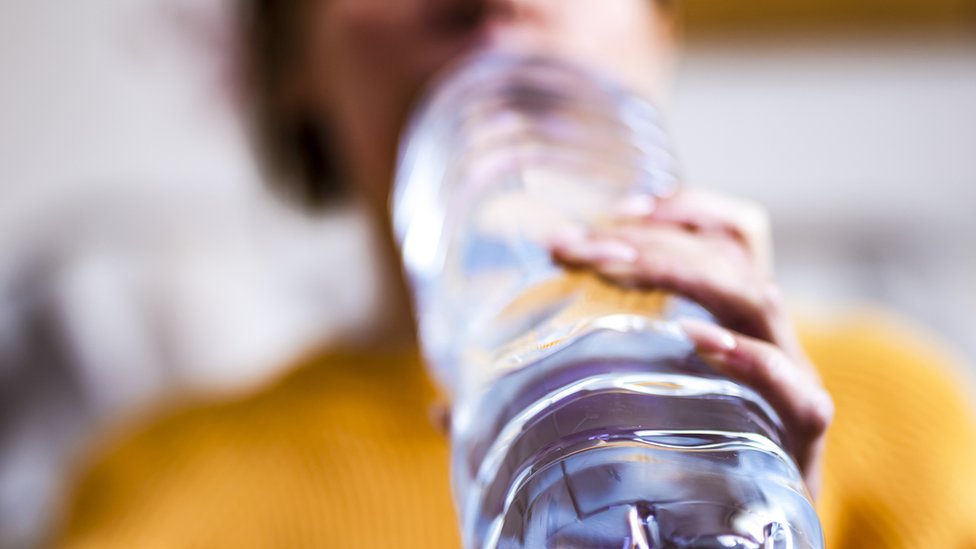Una persona toma agua de una botella