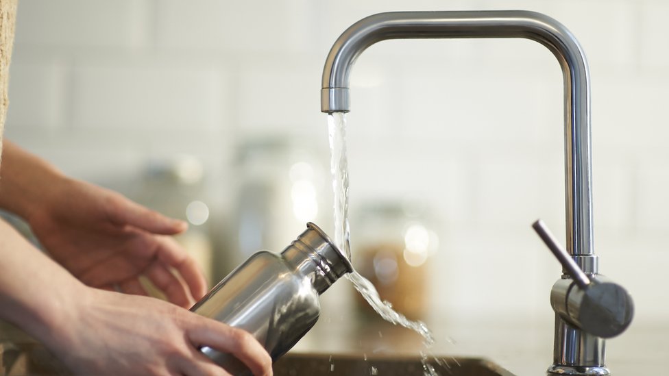 Una persona llena una botella con agua