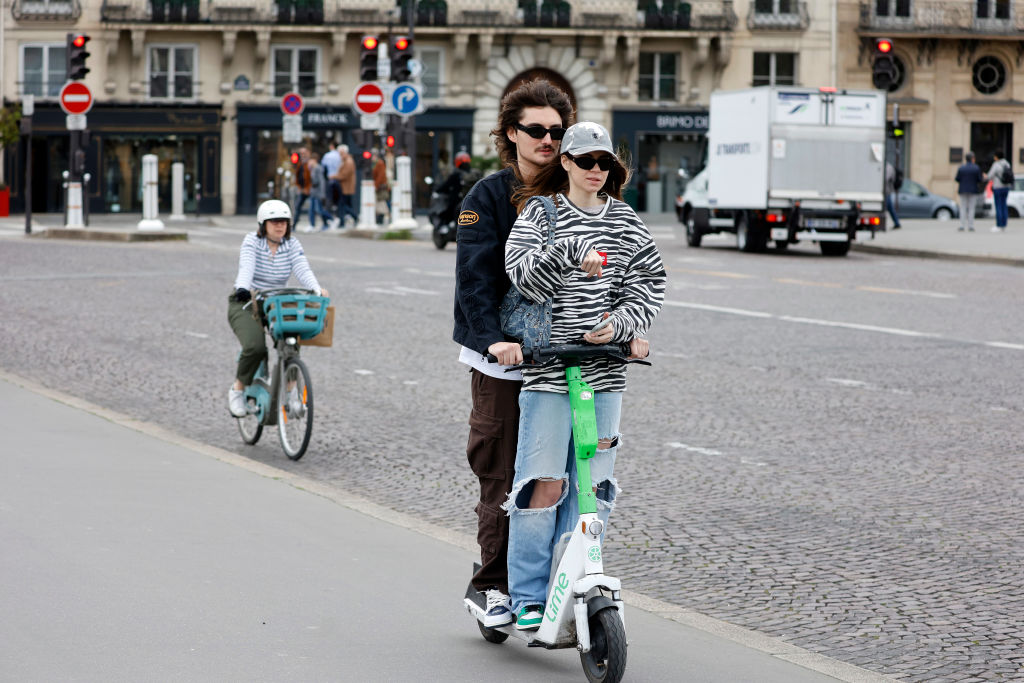 Dos personas subidas en un patinete eléctrico.