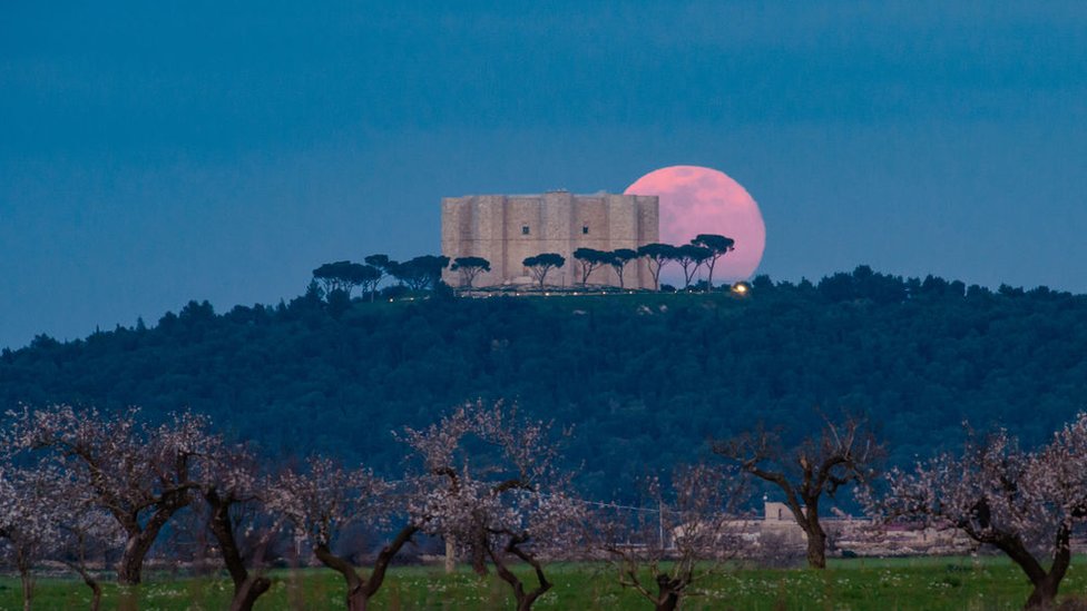 La luna llena sale detrás del Castel del Monte en Andria, Italia.