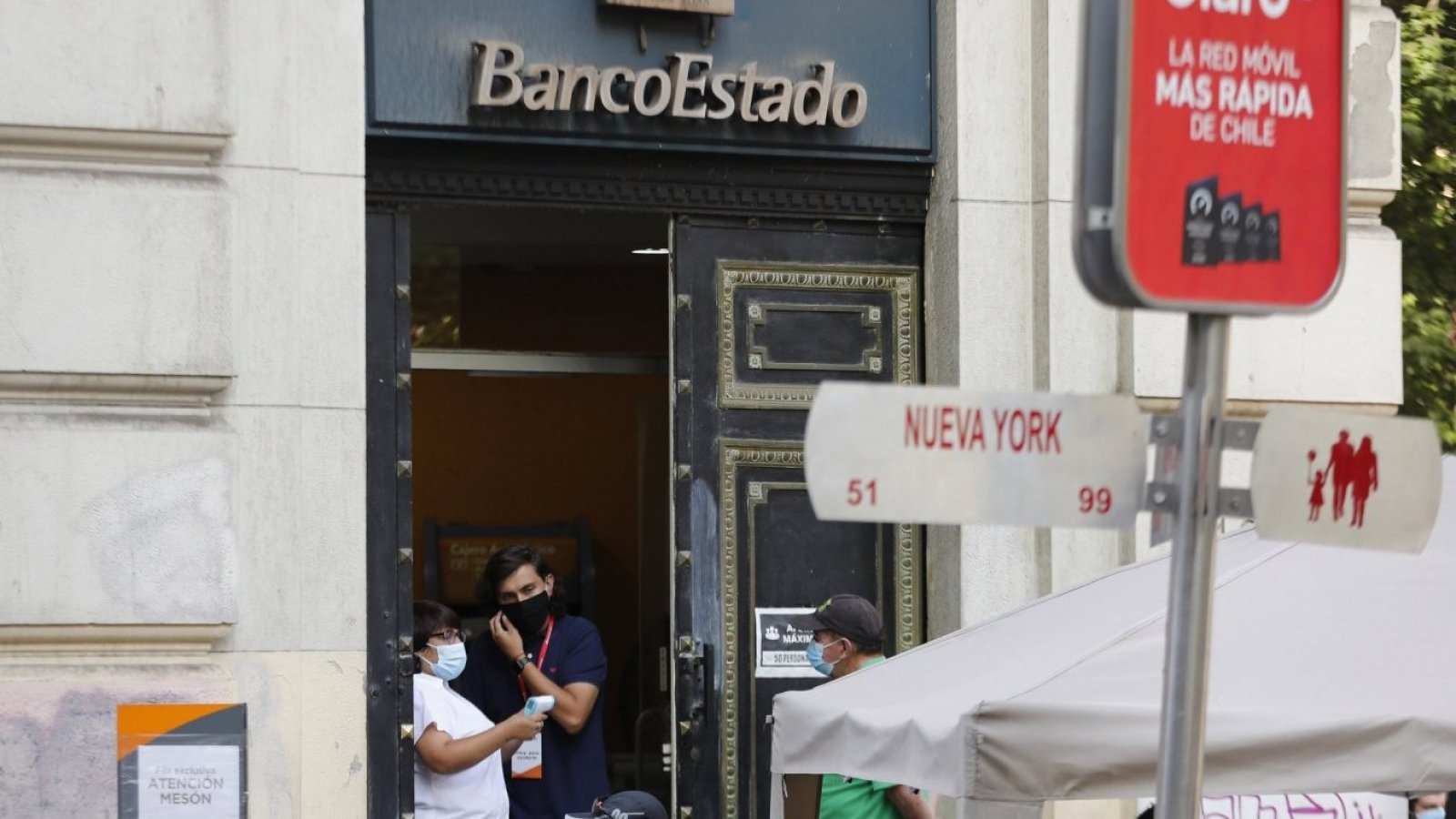 Personas conversan en la entrada de una suscursal de BancoEstado en Santiago Centro