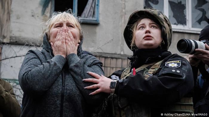 Una mujer junto a una policía frente a uno de los edificios destruidos por el ataque con misiles ruso.
