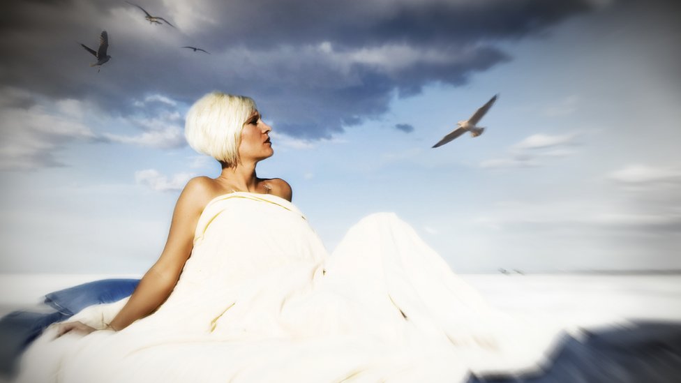 Mujer vestida de blanco con el cielo de fondo