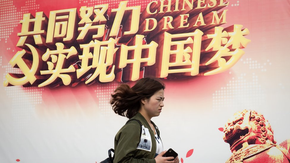 Mujer pasa junto a un cartel del "sueño chino"