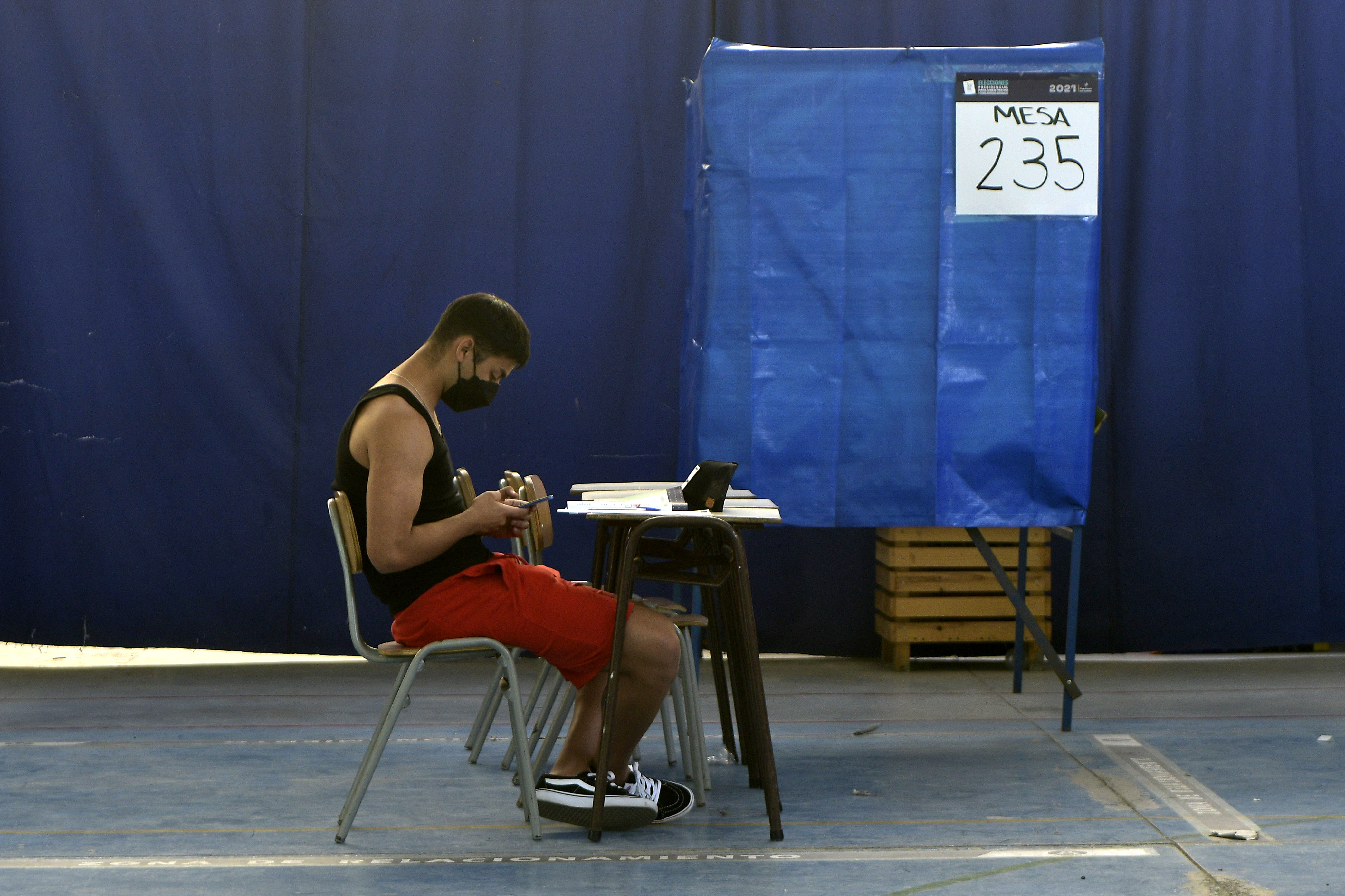 Vocal de mesa revisa el celular en un local de votación.