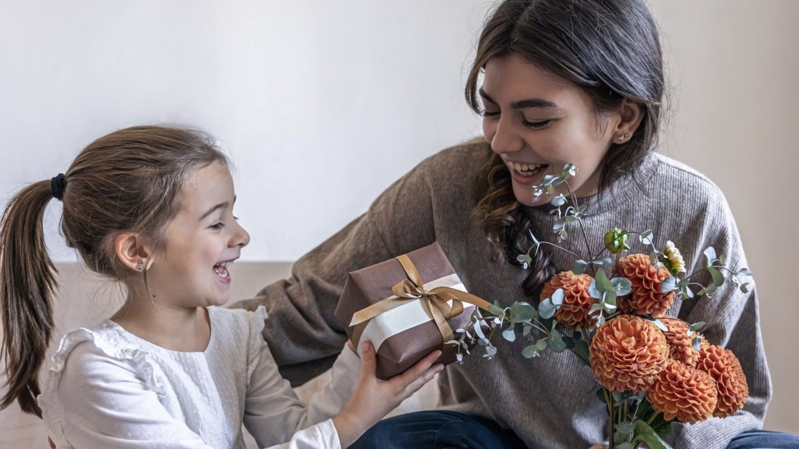 Nina entregándole un regalo y flores a su mamá.