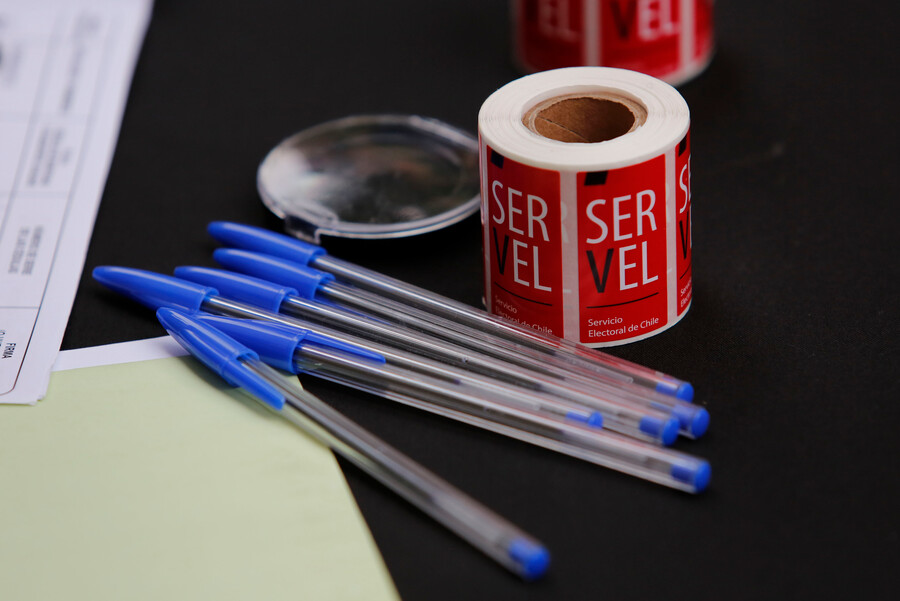 Stickers con el logo del Servel y lápices pasta azules, encima de una mesa.