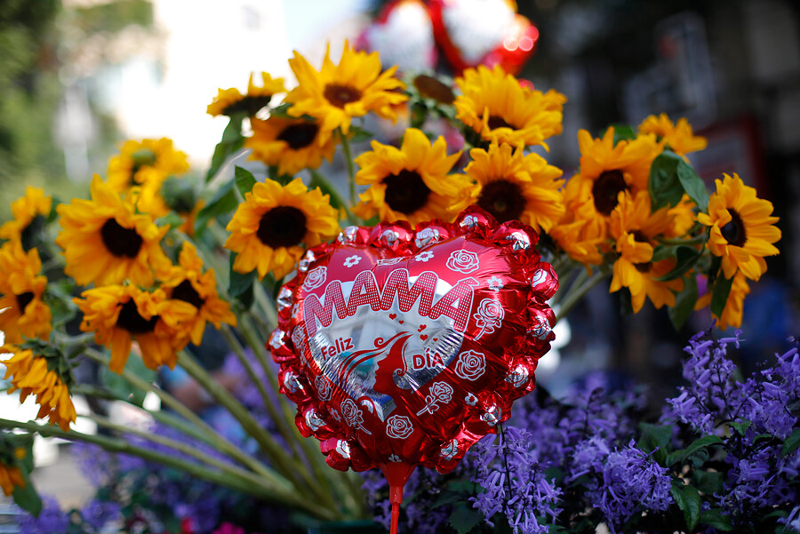 Flores amarillas y un globo rojo en el que se lee la frase "feliz día mamá".