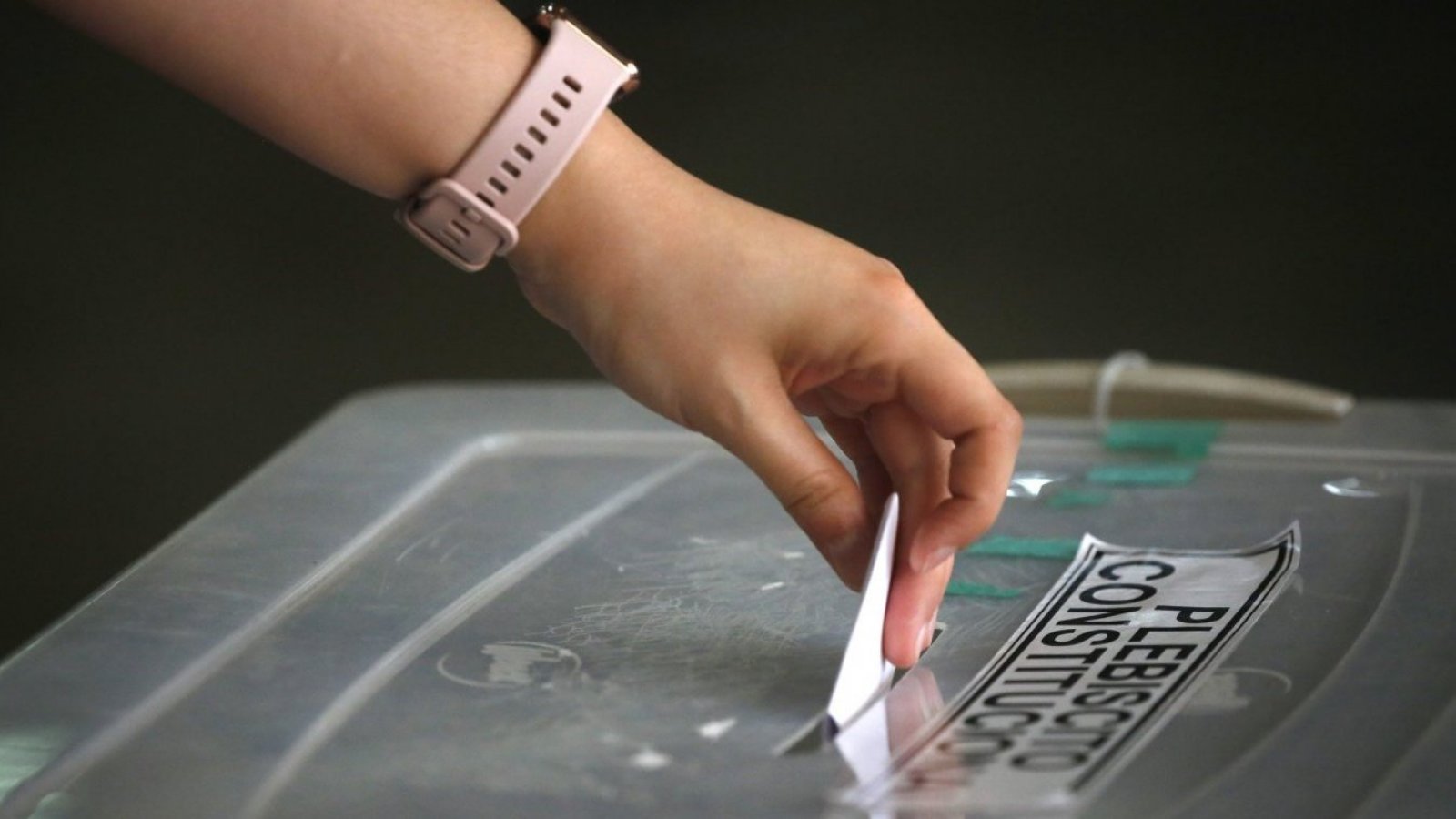 Mano de mujer ingresando un voto a una urna de votación.