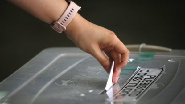 Mano de mujer ingresando un voto a una urna de votación.