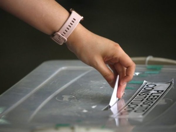 Mano de mujer ingresando un voto a una urna de votación.