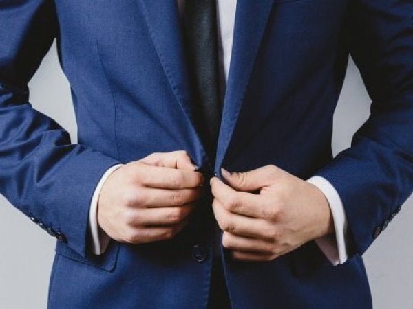 Hombre ajustando el botón de su traje
