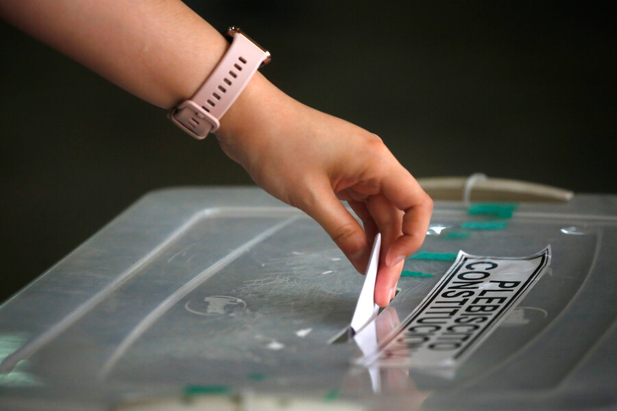 Mano insertando voto en una urna.