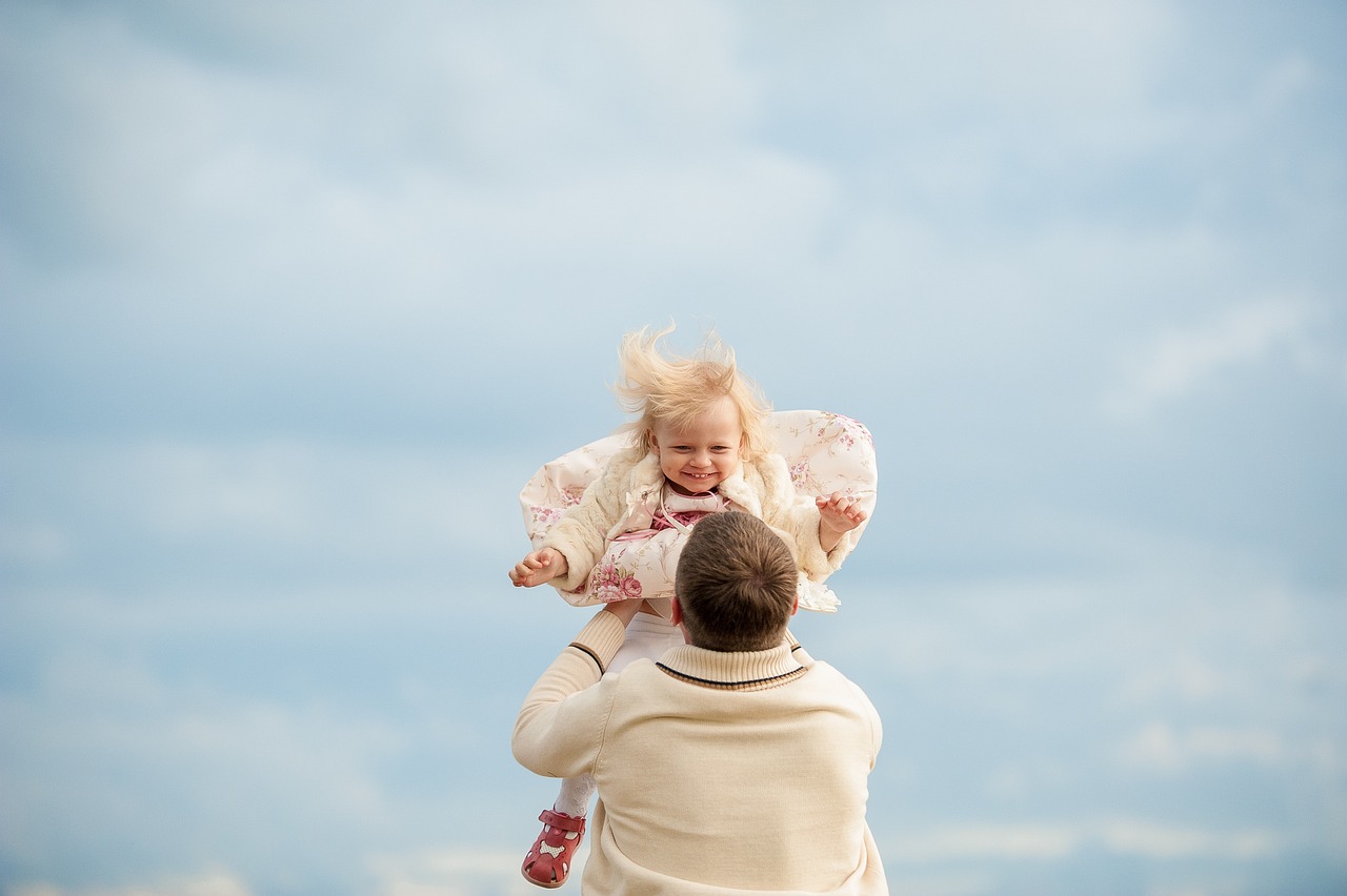 Padre sosteniendo a su hija en el aire