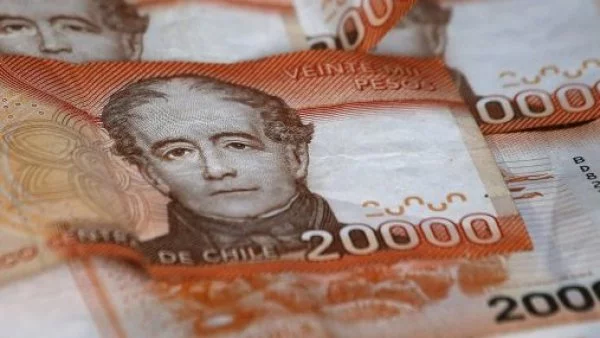 Billetes naranjos de 20 mil pesos apilados uno sobre otro.