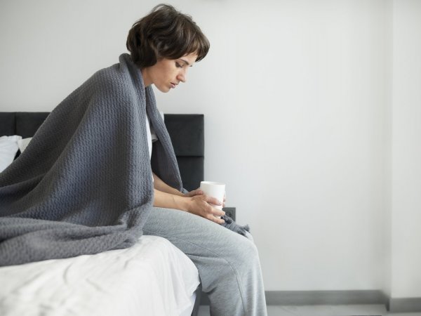 Mujer con anemia sentada en su cama.