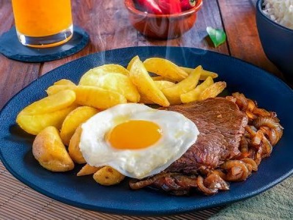 Plato de bistec a lo pobre con carne, cebolla, huevo y papas fritas.