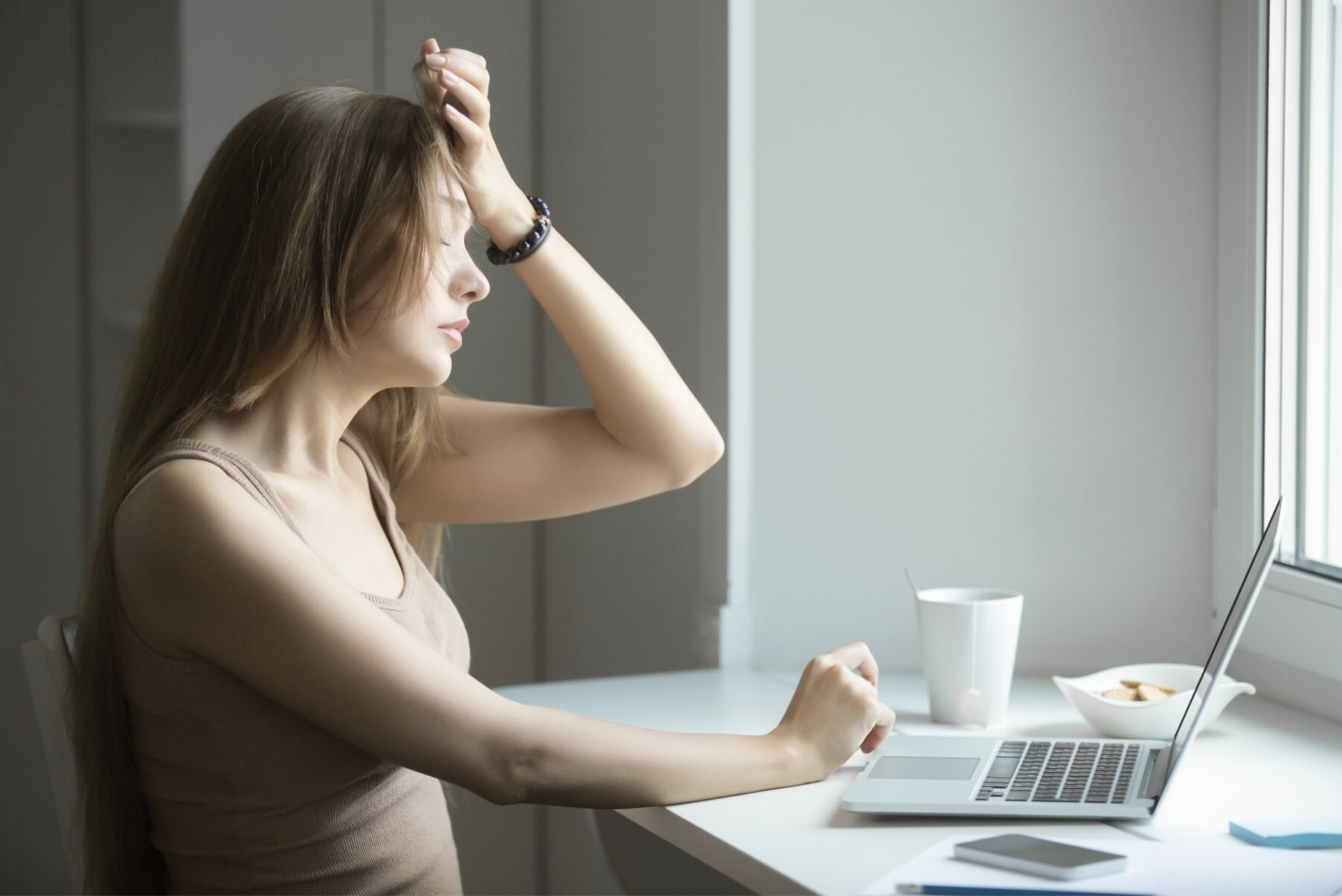 Mujer sentada en su escritorio con la mano en la cabeza