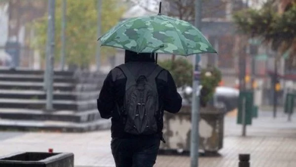 Persona caminando bajo la lluvia con un paragua.