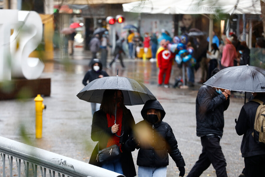 Lluvia en santiago y personas con paraguas caminando.