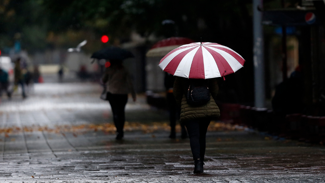 Mujer caminando bajo la lluvia con un paraguas 