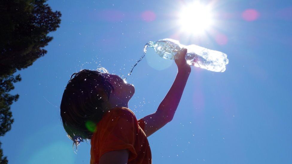 Niño bebiendo agua bajo el sol