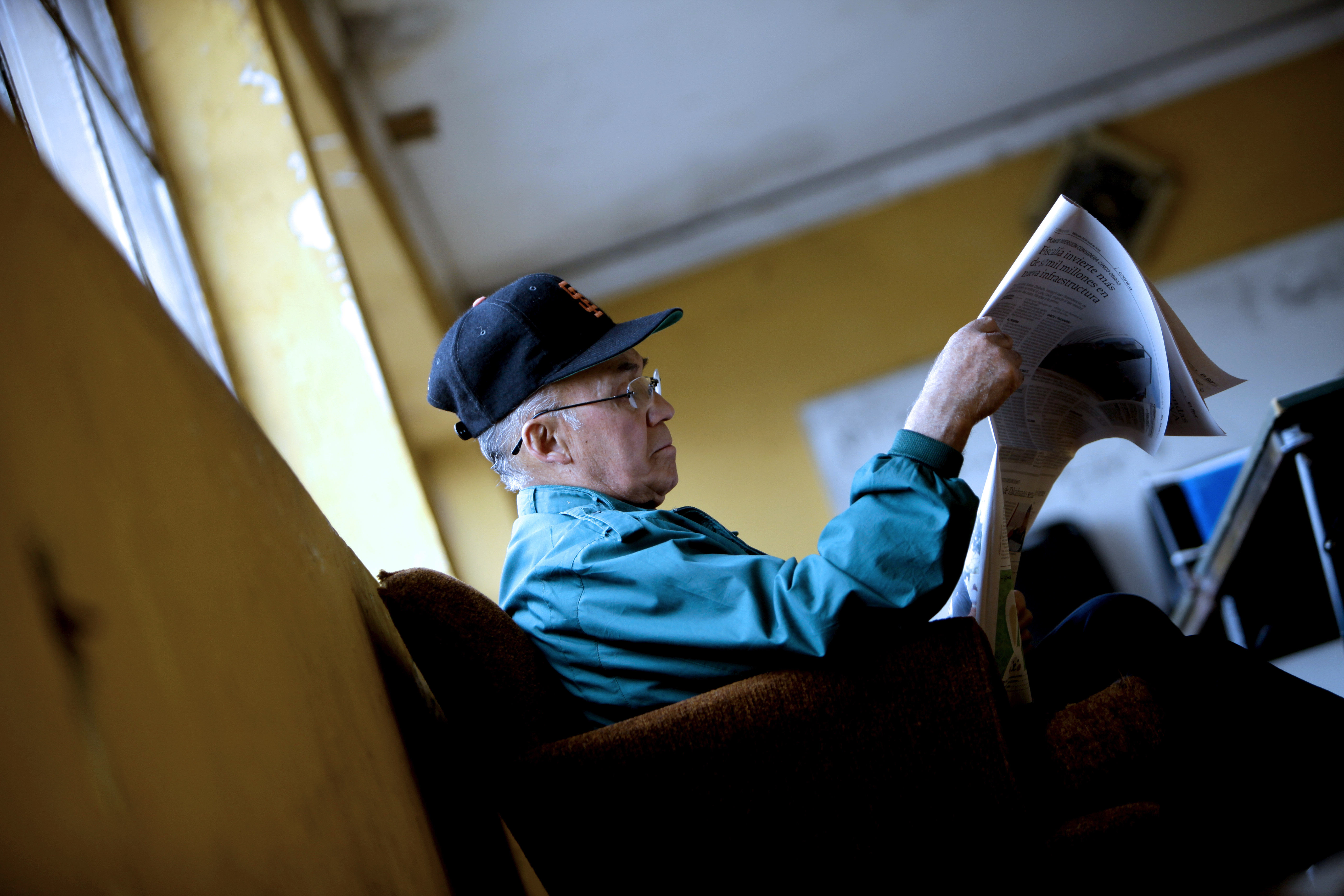 Persona mayor leyendo el diario sentado.