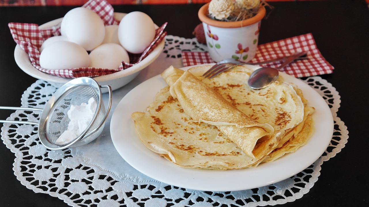 Panqueques sobre plato junto a huevos y harina