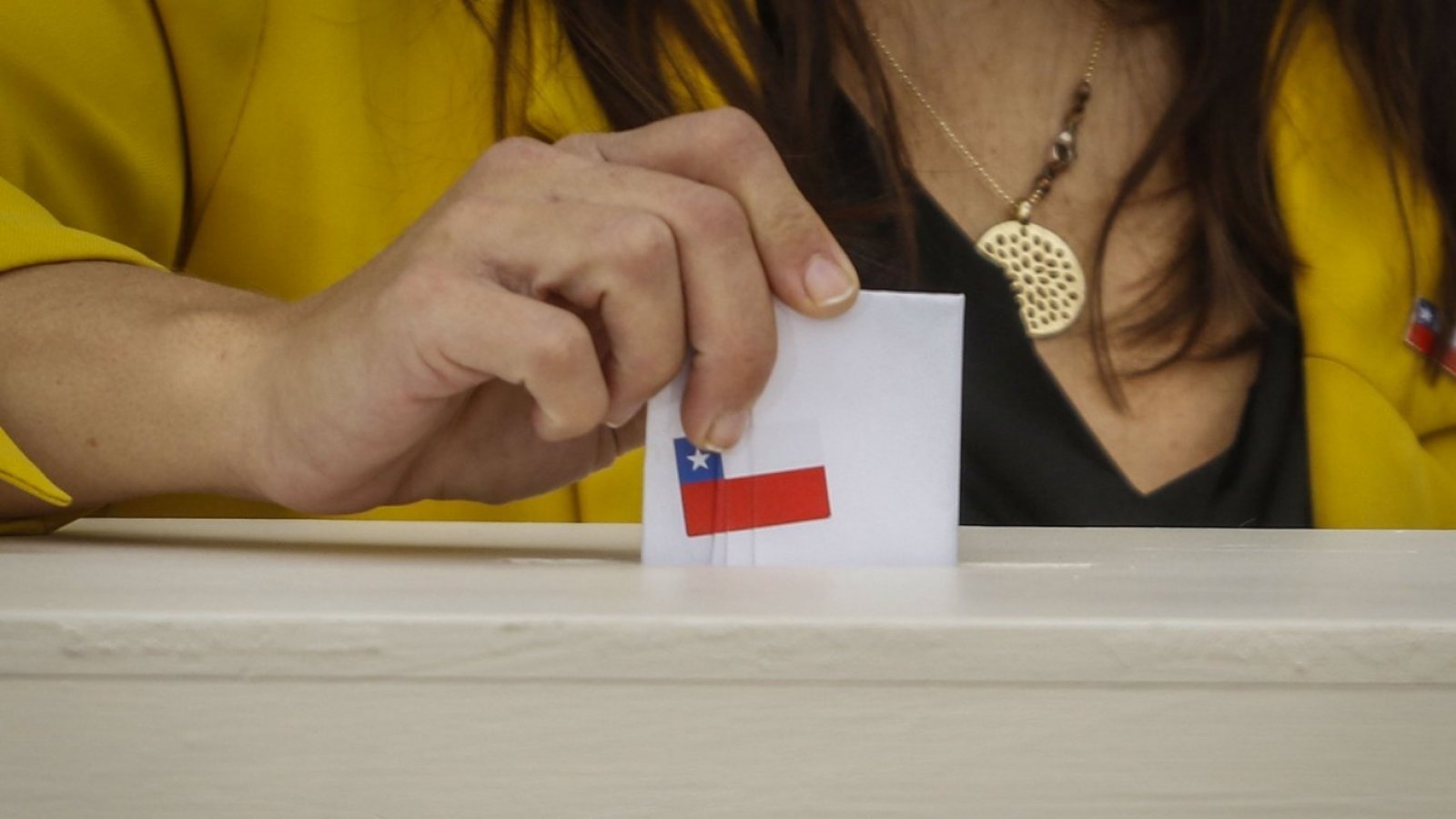 Persona insertando voto dentro de una urna.
