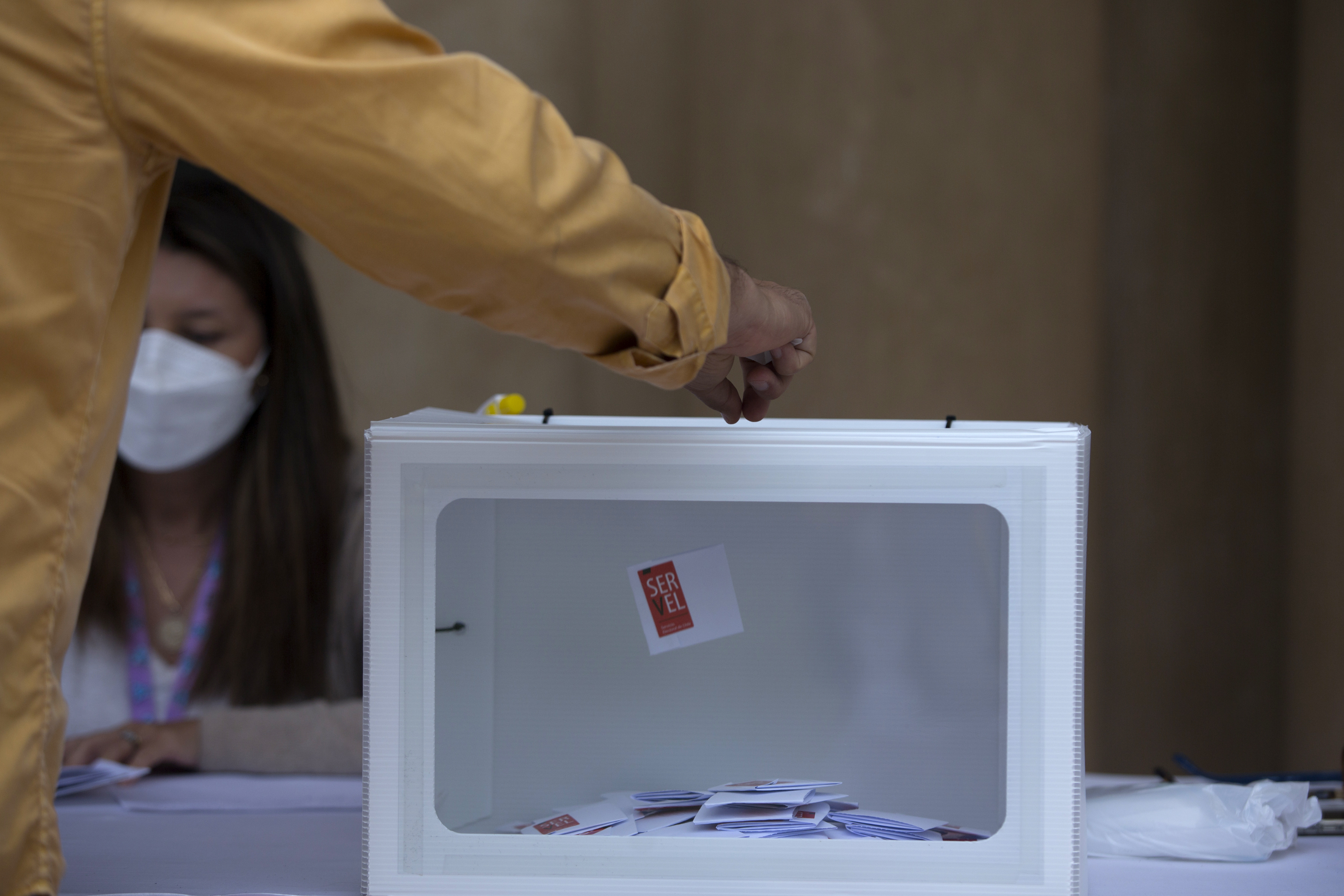Persona insertando su voto en una urna electoral.