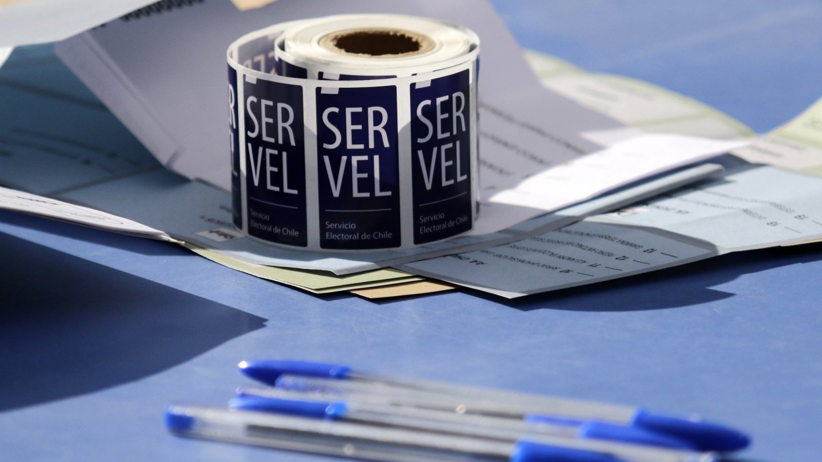 Sticker del Servel con lápices pasta, en una mesa de votación.