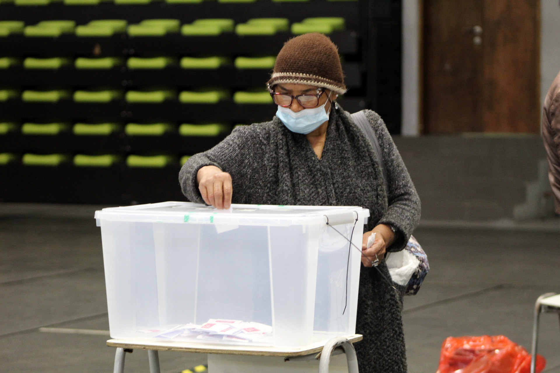 Mujer ingresando su voto en una urna con mascarilla