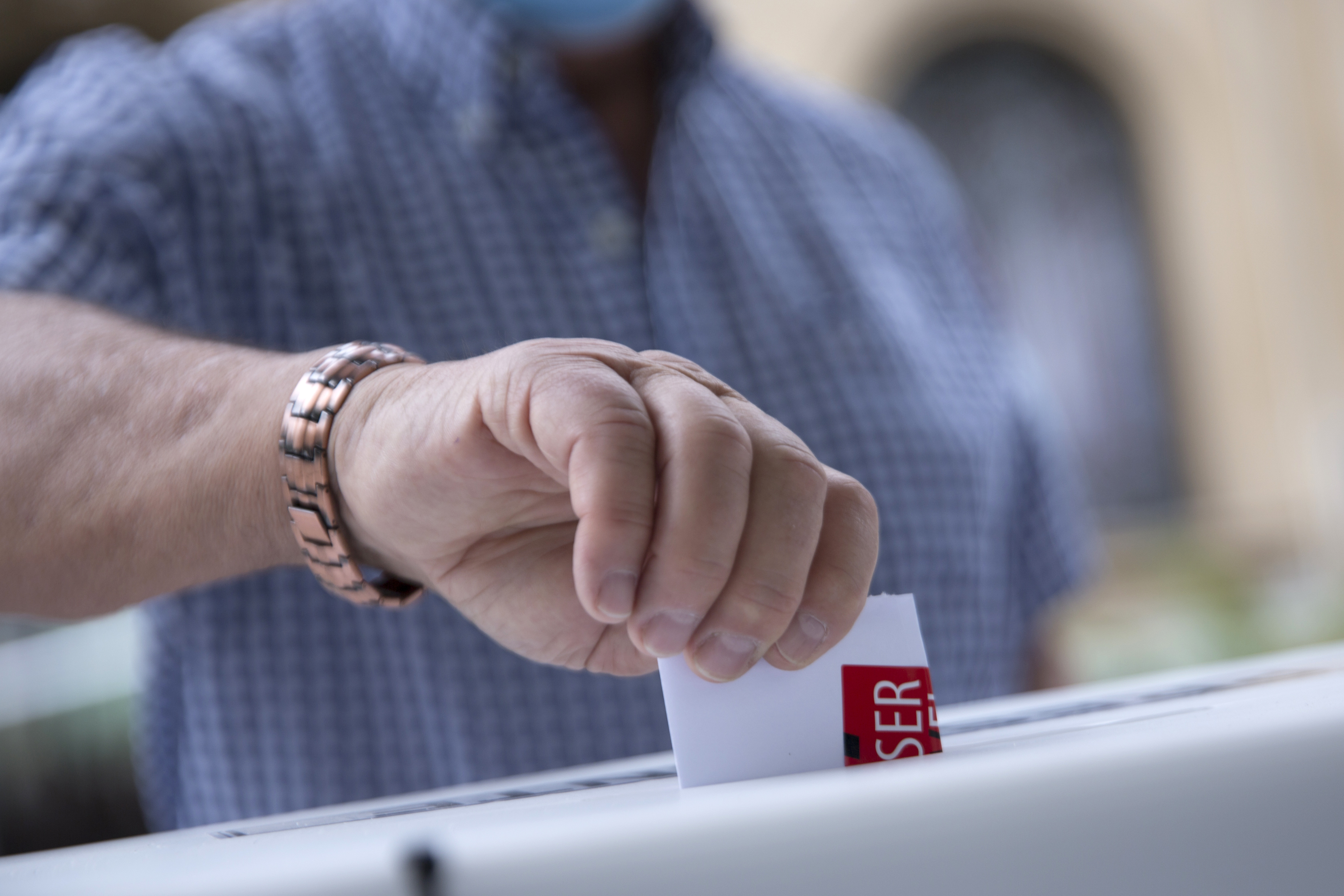 Hombre ingresando su voto en una urna electoral