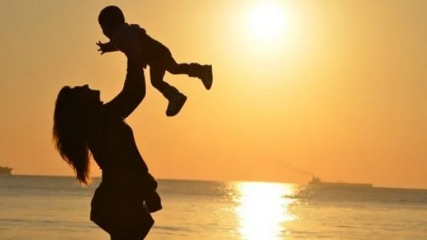 Madre alzando a su hijo en medio de la playa