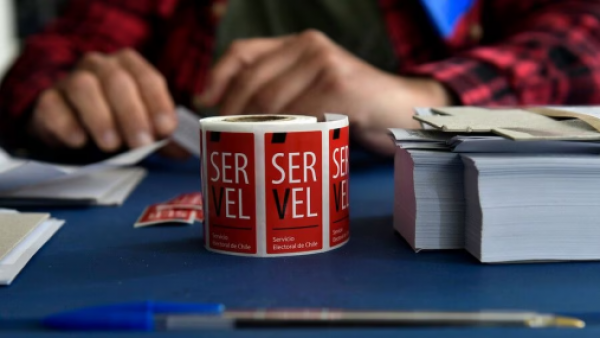 Rollo de stickers del Servel para sellar votos sobre una mesa