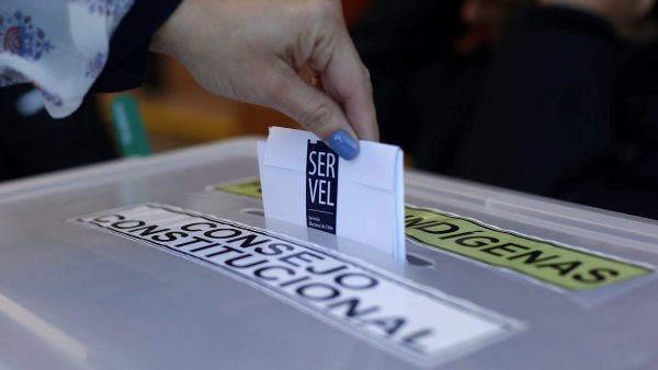 Mano de una persona ingresando su voto en una urna electoral