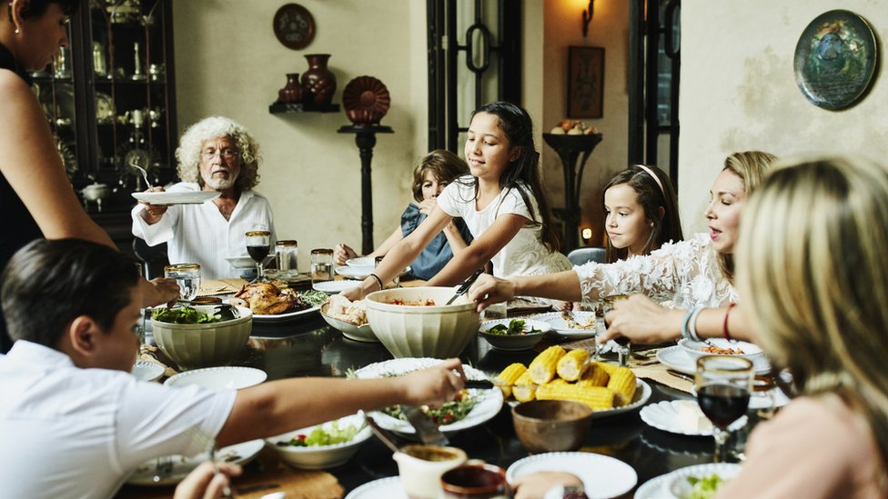 Una familia sentada alrededor de la mesa.