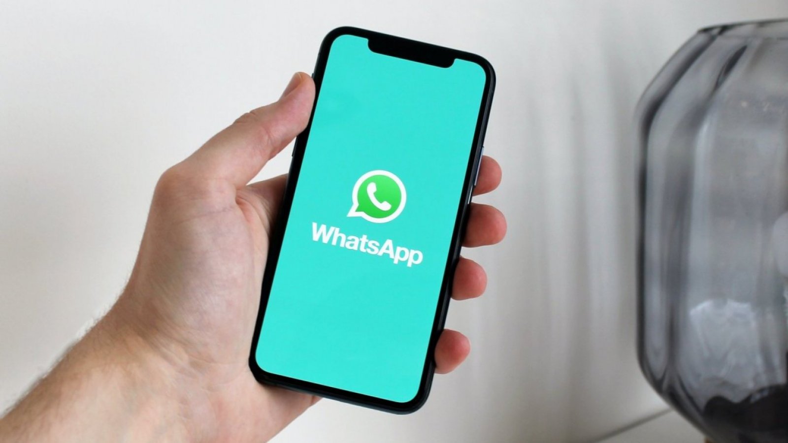 Mano sosteniendo celular con app de WhatsApp abierta