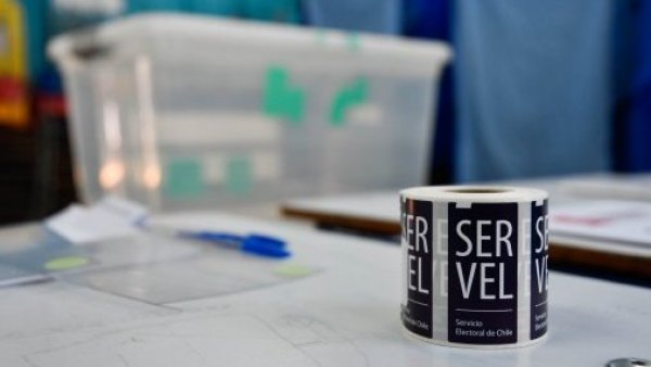 Sticker del Servel al lado de una urna de votación.