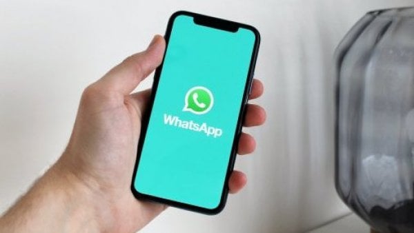 Mano sosteniendo celular con app de WhatsApp abierta