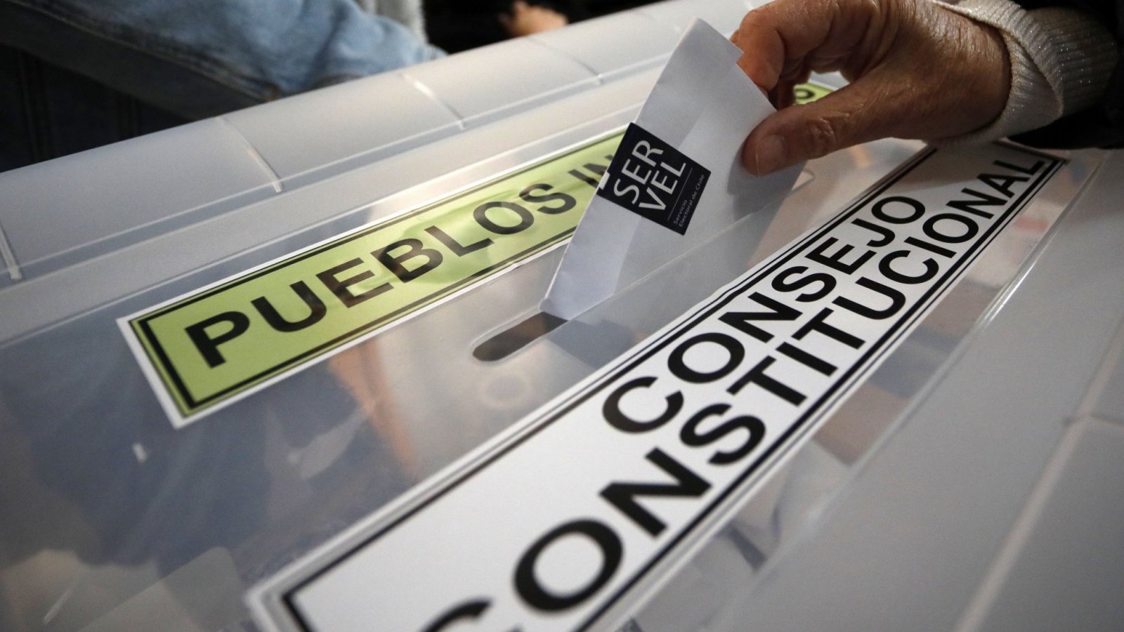Mano ingresando voto en una urna electoral, en donde se lee "Consejo Constitucional".
