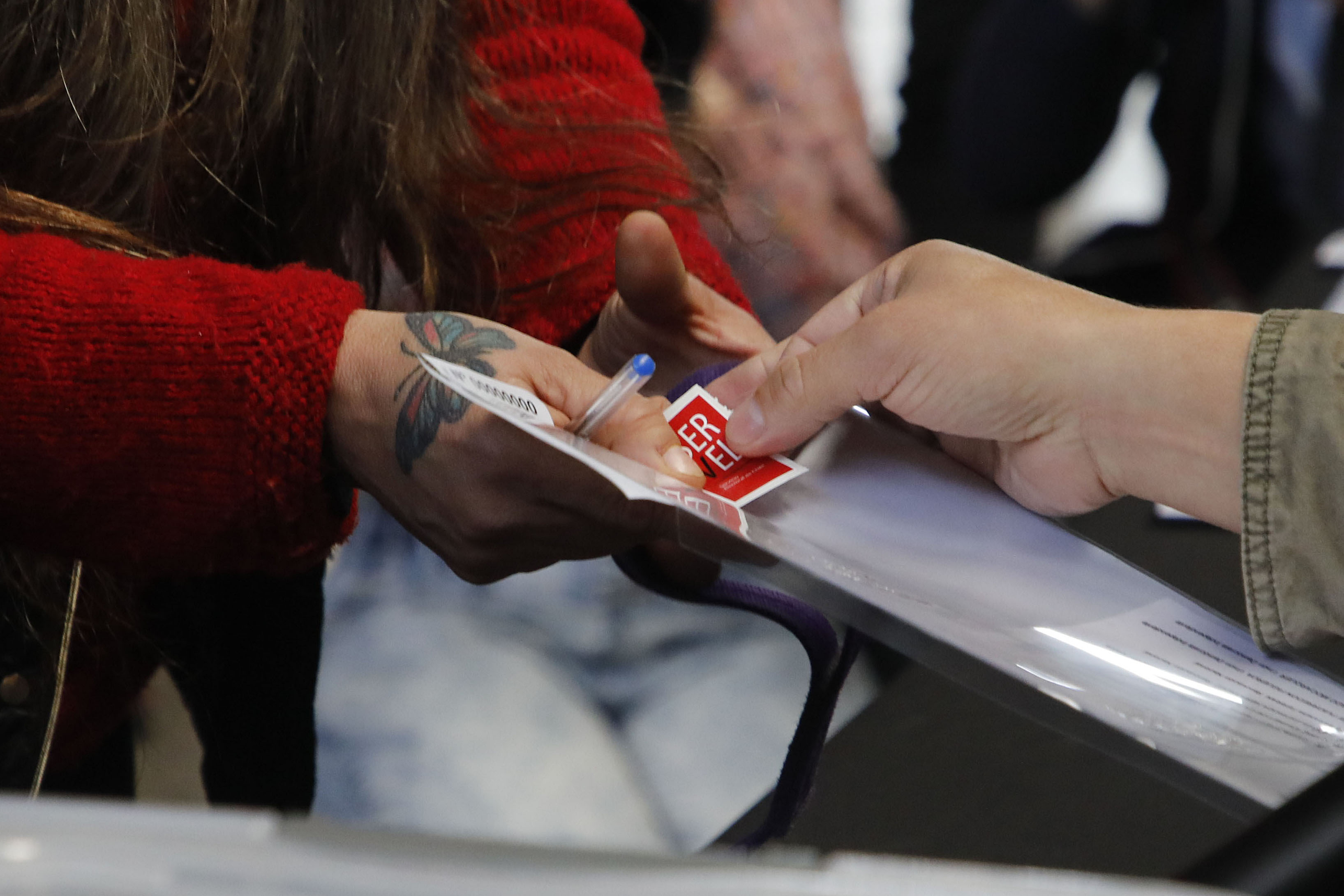 Personas sujetando voto con sticker del Servel.